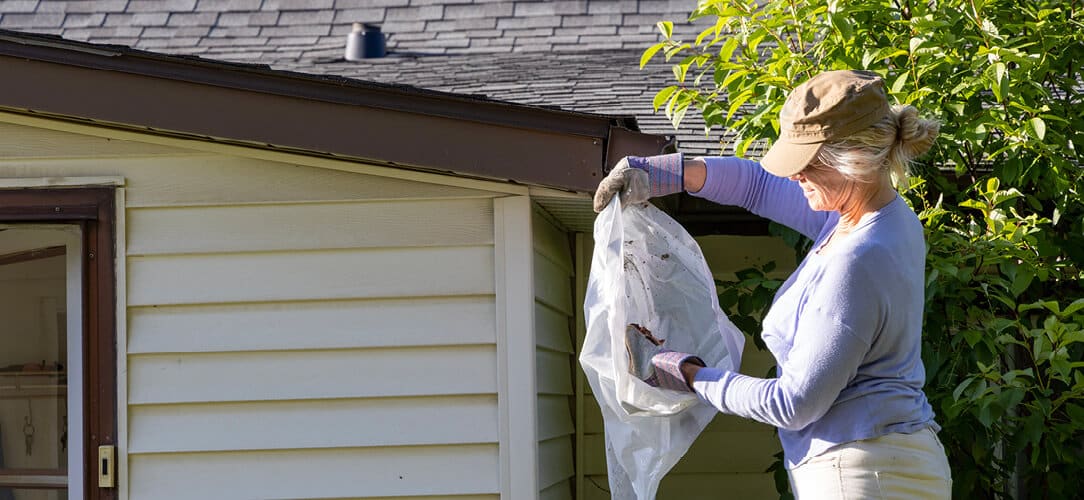 A woman cleaning her roof gutters
