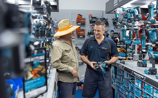 Two Cairns Hardware employees talking and smiling in-store